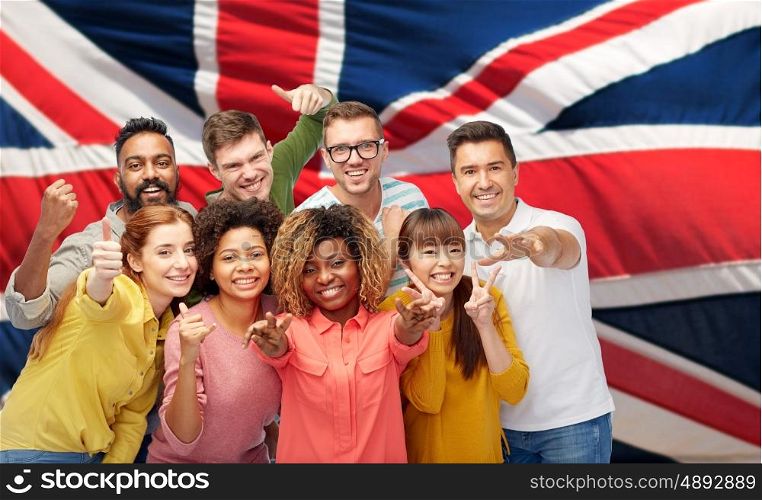 diversity, race, ethnicity and people concept - international group of happy smiling men and women showing thumbs up and peace over british or english flag background