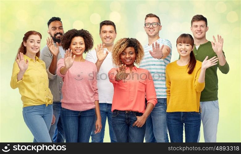 diversity, race, ethnicity and people concept - international group of happy smiling men and women waving hand over summer green lights background