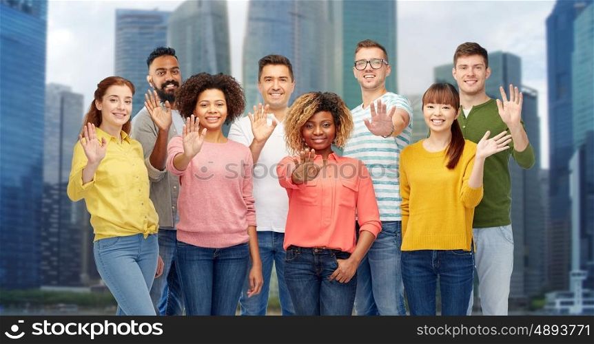 diversity, race, ethnicity and people concept - international group of happy smiling men and women waving hand over singapore city skyscrapers background