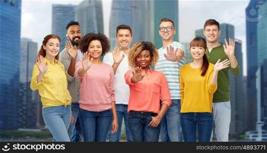diversity, race, ethnicity and people concept - international group of happy smiling men and women waving hand over singapore city skyscrapers background
