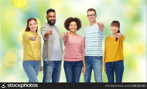 diversity, race, ethnicity and people concept - international group of happy smiling men and women pointing finger on you over green holidays lights background. international group of people pointing on you