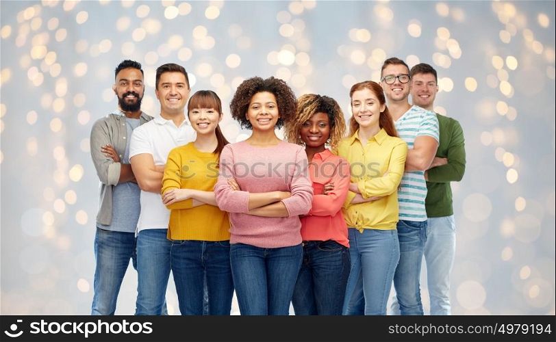 diversity, race, ethnicity and people concept - international group of happy smiling men and women over holidays lights background. international group of happy smiling people