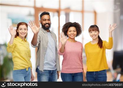 diversity, race, ethnicity and people concept - international group of happy smiling men and women waving hands over office background. international group of happy people waving hands