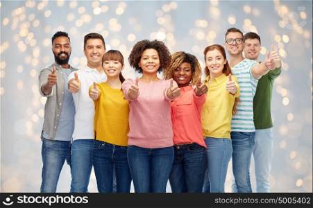 diversity, race, ethnicity and people concept - international group of happy smiling men and women showing thumbs up over holidays lights background. international group of people showing thumbs up