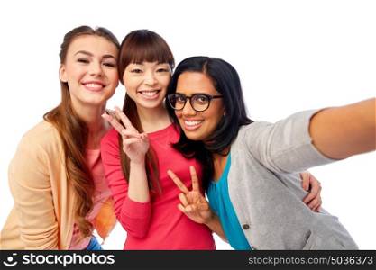 diversity, race, ethnicity and people concept - international group of happy smiling different women over white taking selfie and showing peace hand sign. international group of happy women taking selfie