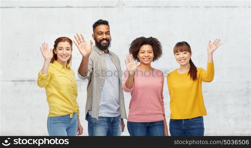 diversity, race, ethnicity and people concept - international group of happy smiling men and women waving hands over stone wall background. international group of happy people waving hands