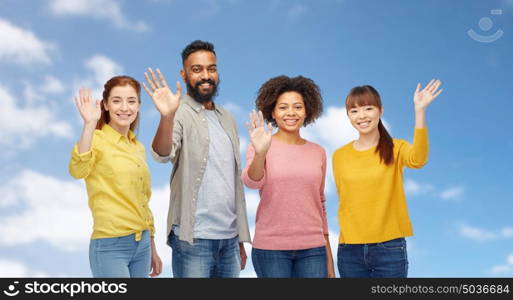 diversity, race, ethnicity and people concept - international group of happy smiling men and women waving hands over blue sky and clouds background. international group of happy people waving hands