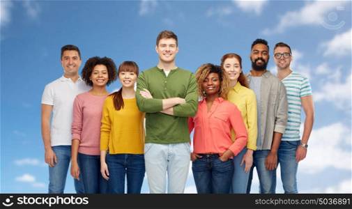 diversity, race, ethnicity and people concept - international group of happy smiling men and women over blue sky and clouds background. international group of happy smiling people