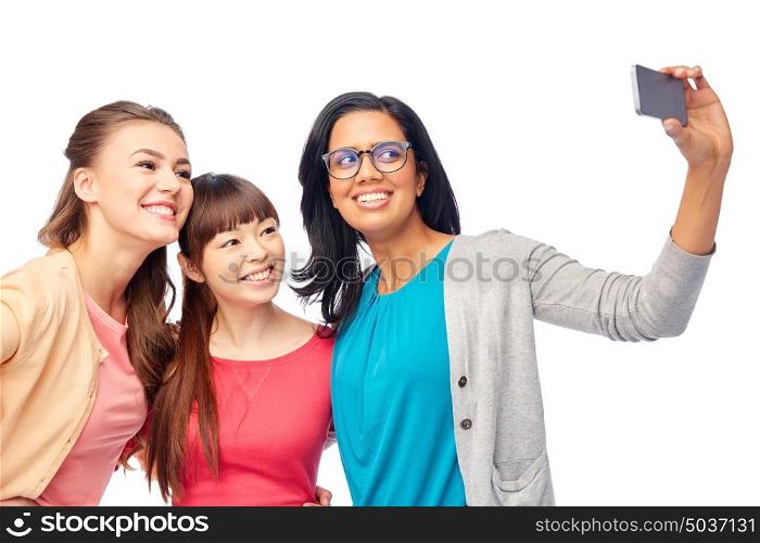 diversity, race, ethnicity and people concept - international group of happy smiling different women over white taking selfie with smartphone. international group of happy women taking selfie
