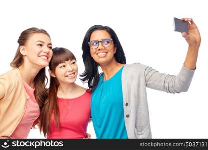 diversity, race, ethnicity and people concept - international group of happy smiling different women over white taking selfie with smartphone. international group of happy women taking selfie