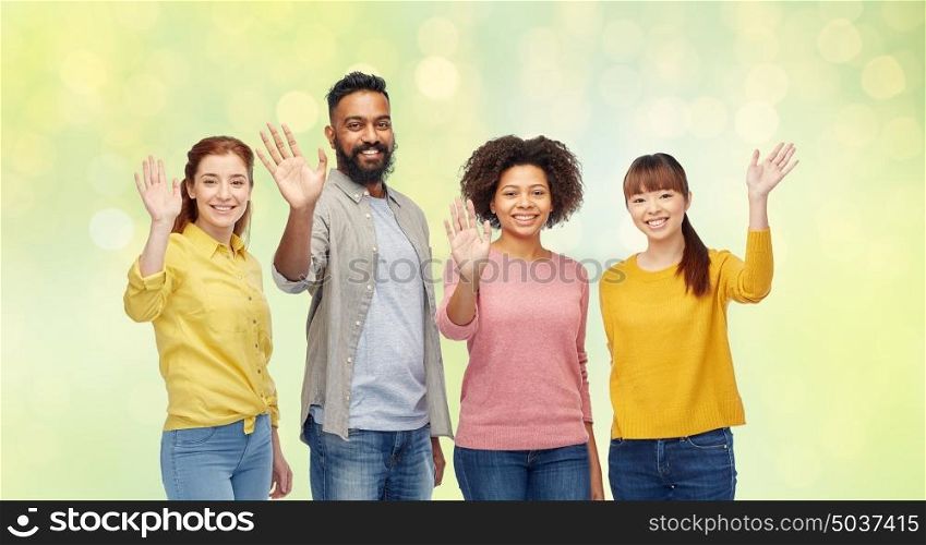diversity, race, ethnicity and people concept - international group of happy smiling men and women waving hands over summer green lights background. international group of happy people waving hands