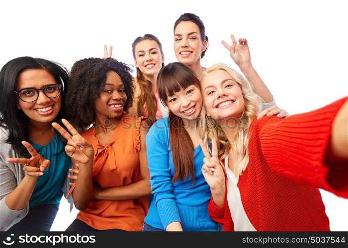 diversity, race, ethnicity and people concept - international group of happy smiling different women over white taking selfie and showing peace hand sign. international group of happy women taking selfie