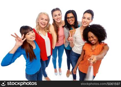 diversity, race, ethnicity and people concept - international group of happy smiling different women over white taking picture with selfie stick. international group of women with selfie stick