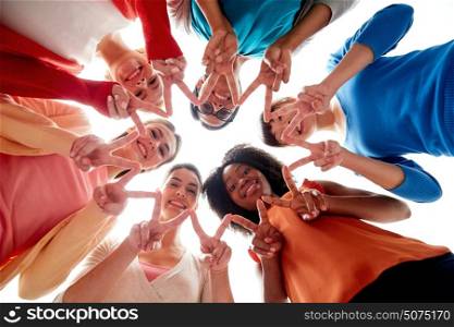 diversity, race, ethnicity and people concept - international group of happy smiling different women lying on floor in circle and showing peace hand sign. international group of happy women showing peace