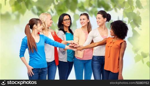 diversity, race, ethnicity and people concept - international group of happy smiling different women holding hands together over green natural background. international group of women with hands together