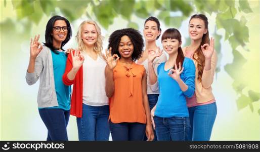 diversity, race, ethnicity and people concept - international group of happy smiling different women showing ok hand sign over green natural background. international group of happy women showing ok