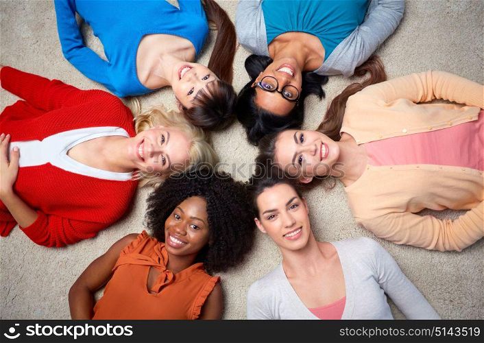 diversity, race, ethnicity and people concept - international group of happy smiling different women lying on floor in circle. international group of happy women lying on floor