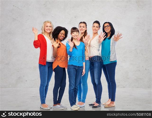 diversity, race, ethnicity, gesture and people concept - international group of happy smiling different women waving hands over gray concrete wall background. international group of happy women waving hands