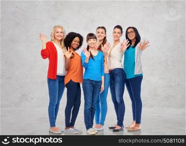 diversity, race, ethnicity, gesture and people concept - international group of happy smiling different women waving hands over gray concrete wall background. international group of happy women waving hands