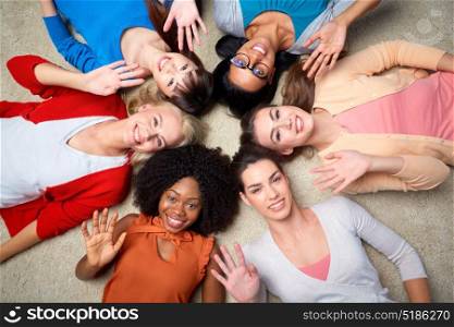diversity, race, ethnicity, gesture and people concept - international group of happy smiling different women lying on floor in circle and waving hands. international group of happy women waving hands