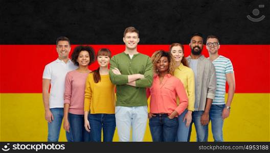 diversity, race, ethnicity, immigration and people concept - international group of happy smiling men and women over german flag background. international group of people over german flag