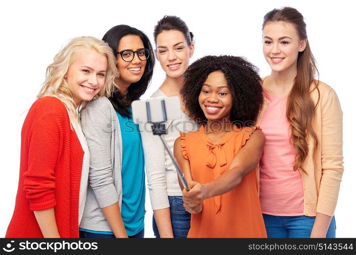 diversity, race, ethnicity, technology and people concept - international group of happy smiling different women over white taking picture with smartphone on selfie stick. international group of happy women taking selfie