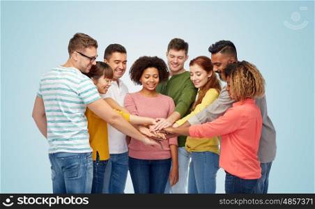 diversity, teamwork, cooperation, ethnicity and people concept - international group of happy smiling men and women holding hands together over blue background
