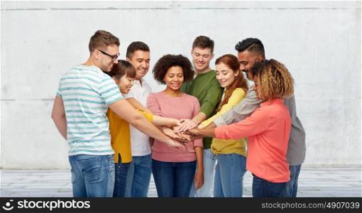 diversity, teamwork, cooperation, ethnicity and people concept - international group of happy smiling men and women holding hands together over wall background. international group of happy people holding hands