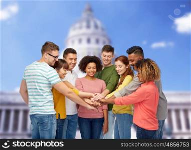 diversity, teamwork, race, ethnicity and people concept - international group of happy smiling men and women holding hands together over united states capitol background