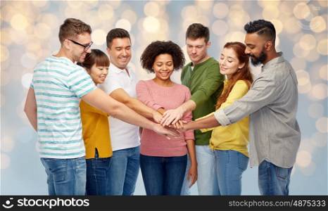 diversity, teamwork, race, ethnicity and people concept - international group of happy smiling men and women holding hands together over holidays lights background