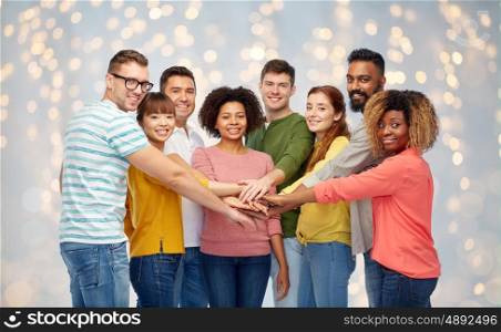diversity, teamwork, race, ethnicity and people concept - international group of happy smiling men and women holding hands together over holidays lights background
