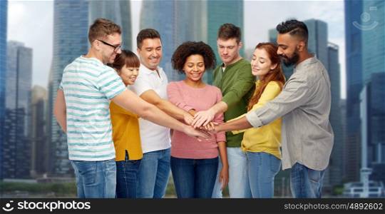 diversity, teamwork, race, ethnicity and people concept - international group of happy smiling men and women holding hands together over singapore city skyscrapers background