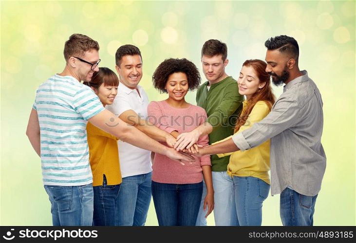 diversity, teamwork, race, ethnicity and people concept - international group of happy smiling men and women holding hands together over summer green lights background
