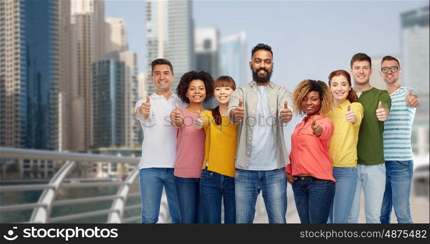 diversity, travel, tourism and people concept - international group of happy smiling men and women showing thumbs up over dubai city background