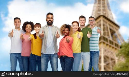 diversity, travel, tourism and people concept - international group of happy smiling men and women showing thumbs up over eiffel tower background. people showing thumbs up over eiffel tower