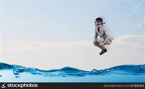 Diving businessman . Young businessman in suit and diving mask jumping in water