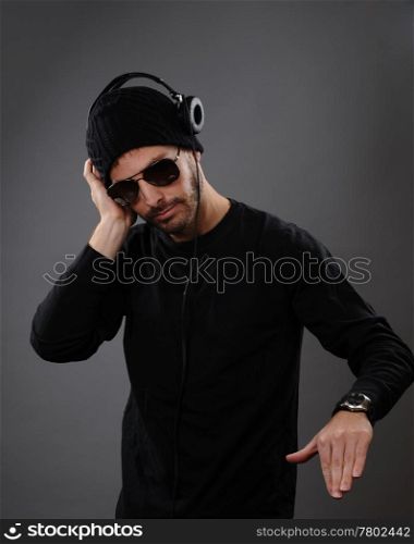 DJ listening to headphones on a dark background. His hand is out as he is about to spin a record.