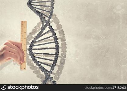 Dna molecule. Close up of male hand measuring DNA molecule with ruler