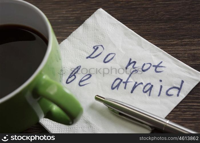 Do not be afraid. Message written on napkin and coffee cup on wooden napkin