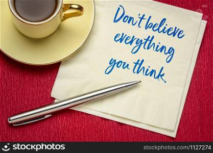 Do not believe everything you think - handwriting on a napkin with a cup of coffee, warning concept