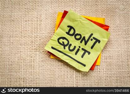 Do not quit advice or reminder on a sticky note against burlap canvas