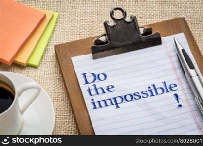Do the impossible advice or encouragement on clipboard with a pen, coffee and sticky notes against burlap canvas - motivational concept