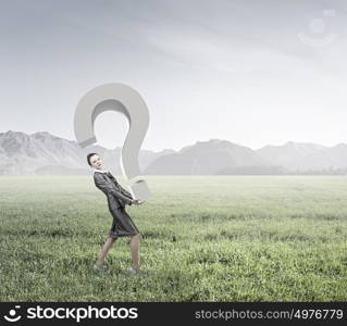 Do you have question. Attractive businesswoman carrying big stone question mark