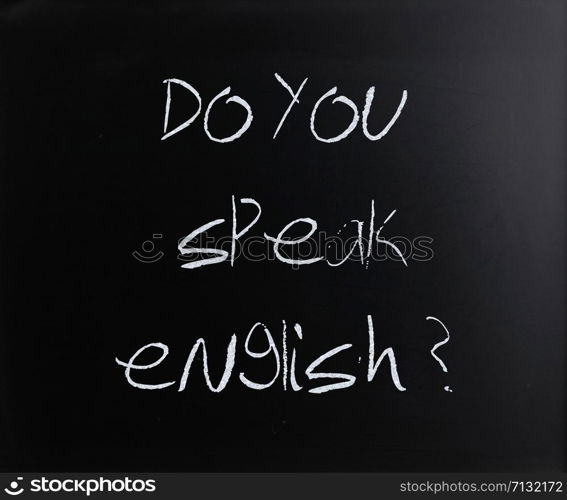 ""Do you speak english" handwritten with white chalk on a blackboard."