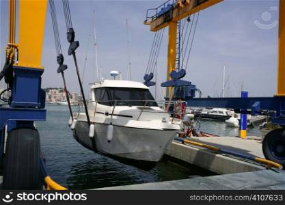 Dock crane elevating a fishing boat in Mediterranean marina