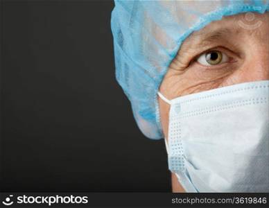 Doctor&#39;s face with mask and cap on grey background
