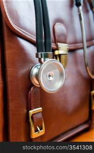 Doctor&acute;s case with stethoscope against wooden background