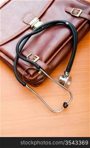 Doctor&acute;s case with stethoscope against wooden background