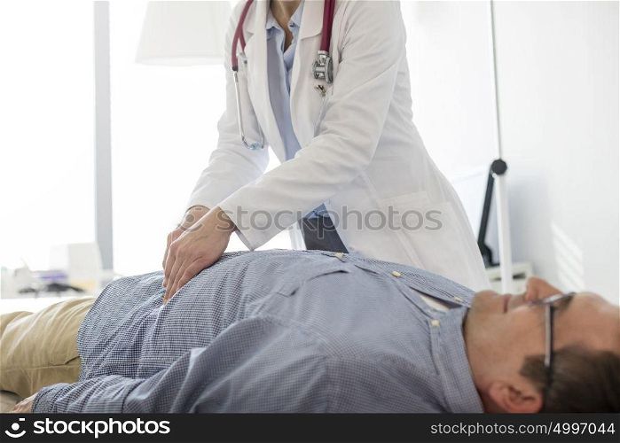 Doctor analyzing abdomen of patient in examination room at hospital
