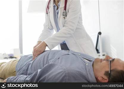 Doctor analyzing abdomen of patient in examination room at hospital